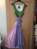 Green and white garment on a hanger next to a purple skirt on a wooden surface.